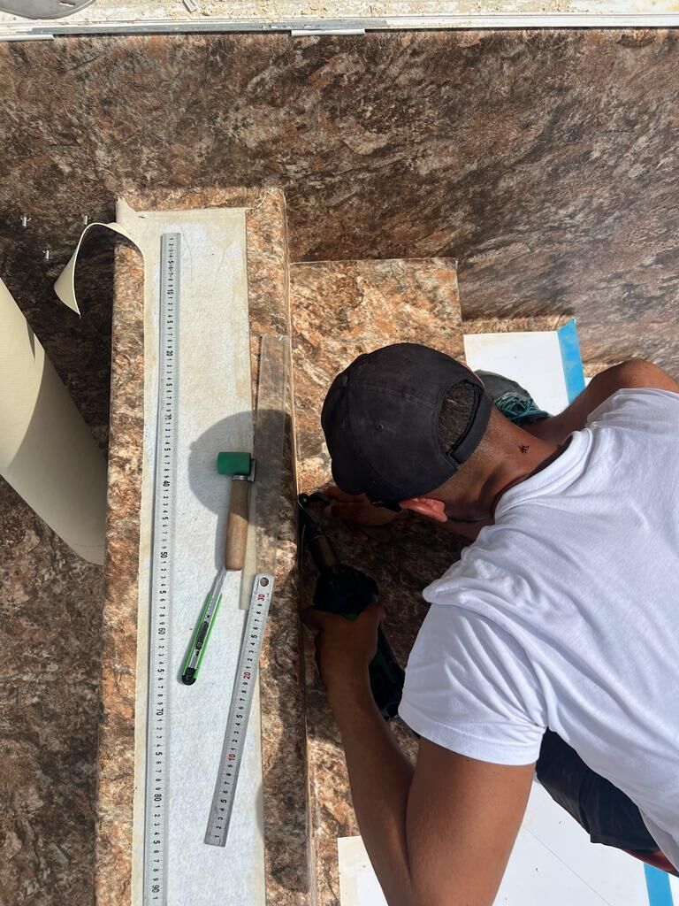 Poseur de piscine ajustant la membrane PVC armée sur une arête