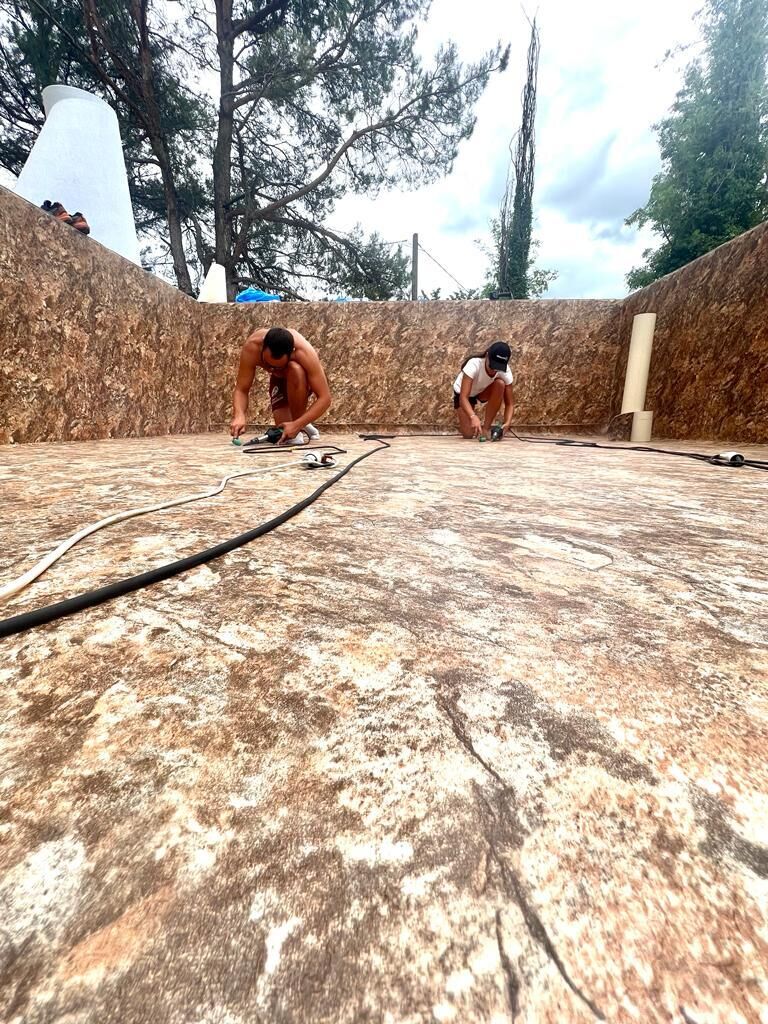Techniciens en train de souder à chaud la membrane armée sur le fond